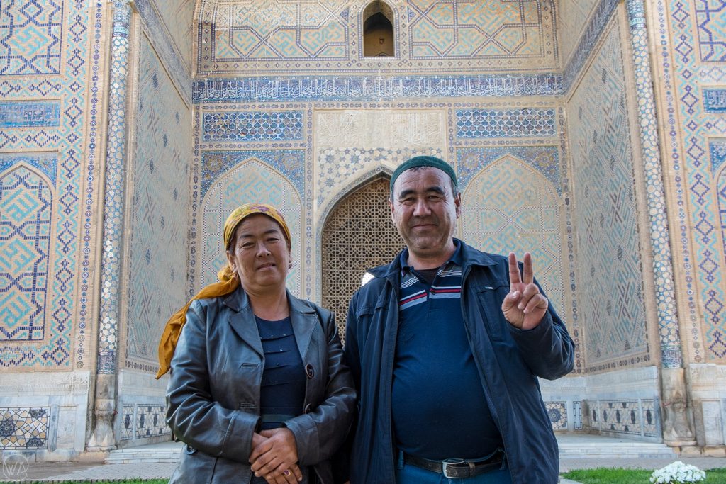 Uzbek couple posing for a photo in front of the mosque in Samarkand, Uzbekistan